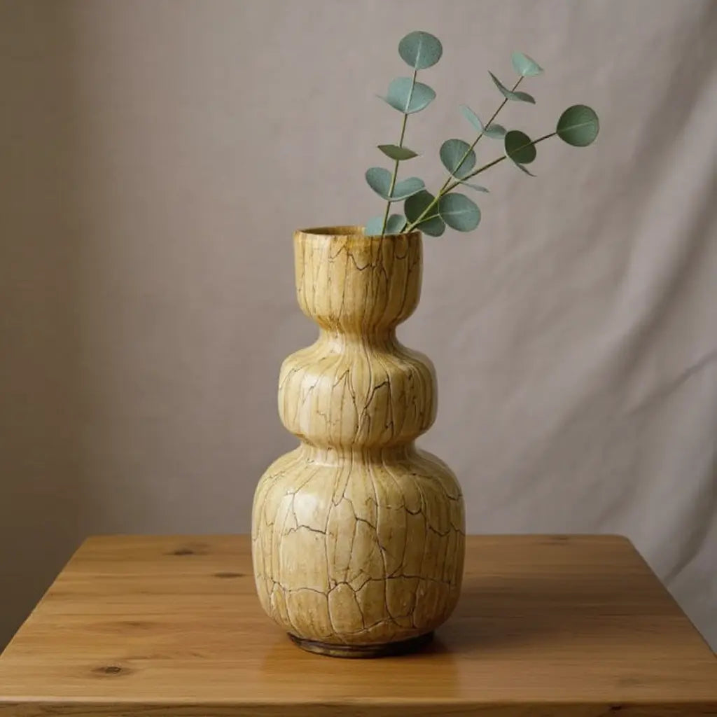 Vaas Liona H25 Walnut: houten, gebarsten keramische stijlvaas met ronde vormen en een tak eucalyptus erin.